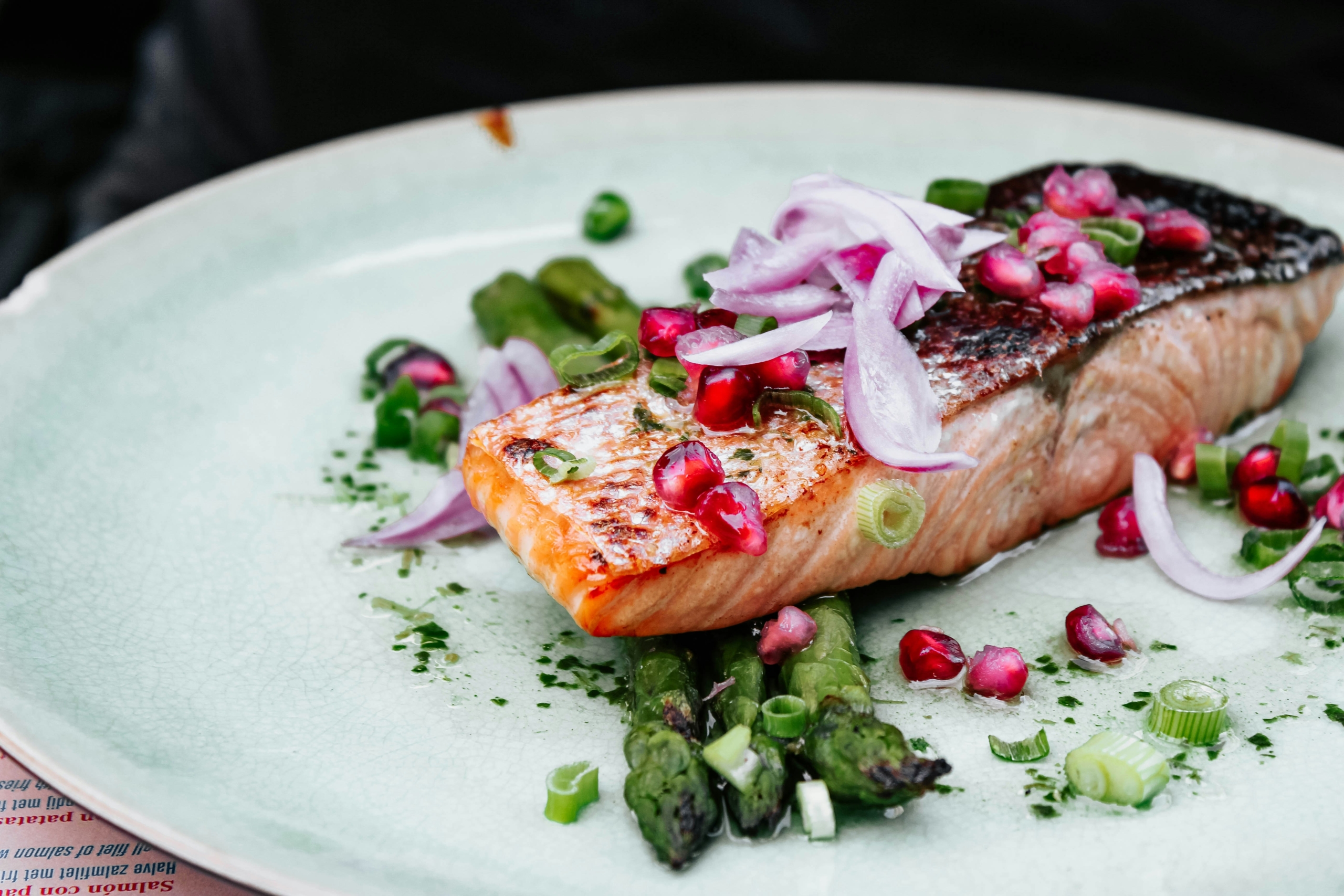 Grilled salmon fillet with asparagus and pomegranate, highlighting nutrition strategies for sleep and mental health.